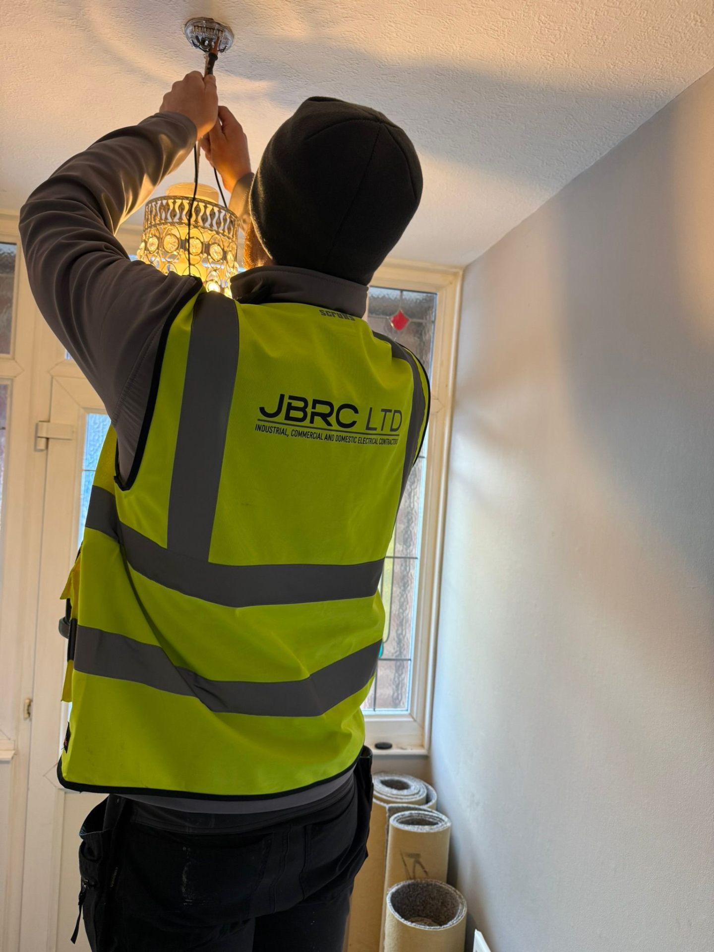 JBRC NICEIC engineer in branded hi-vis reterminating a ceiling pendant during a landlord EICR at a Nottingham rental property
